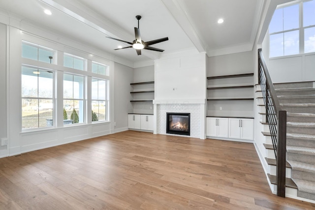 unfurnished living room featuring ornamental molding, light wood-type flooring, ceiling fan, and beamed ceiling