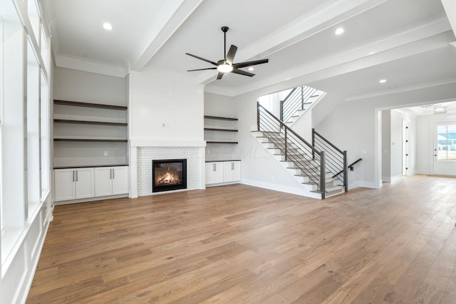 unfurnished living room featuring ornamental molding, light wood-type flooring, and beam ceiling