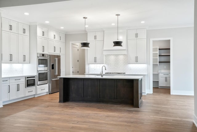 kitchen with hanging light fixtures, appliances with stainless steel finishes, light countertops, and white cabinets