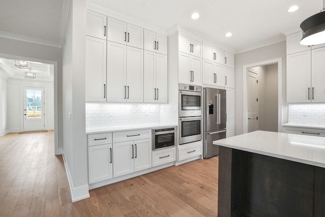 kitchen featuring light wood-style floors, white cabinets, light countertops, appliances with stainless steel finishes, and crown molding