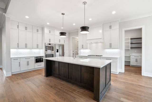 kitchen featuring appliances with stainless steel finishes, light countertops, custom exhaust hood, and white cabinetry