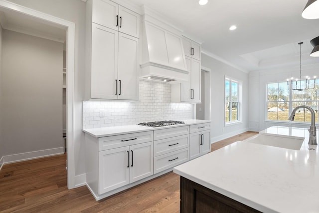 kitchen with pendant lighting, a sink, white cabinetry, and custom range hood