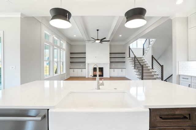 kitchen with pendant lighting, light countertops, a large fireplace, open floor plan, and a sink