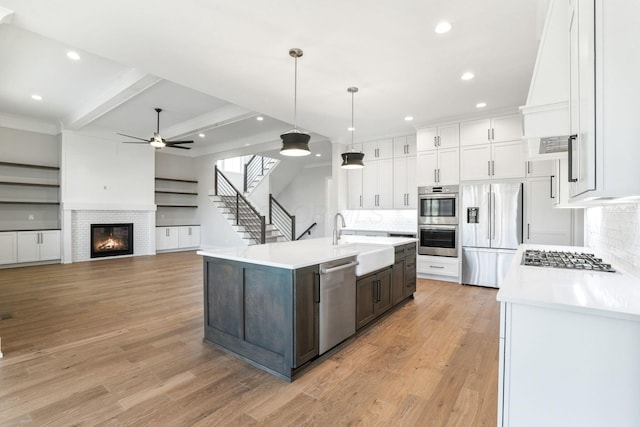 kitchen with a sink, white cabinetry, light countertops, appliances with stainless steel finishes, and an island with sink