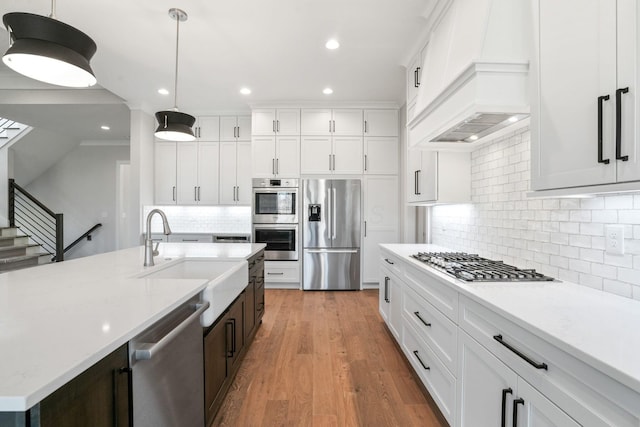 kitchen featuring stainless steel appliances, hanging light fixtures, a sink, and white cabinetry