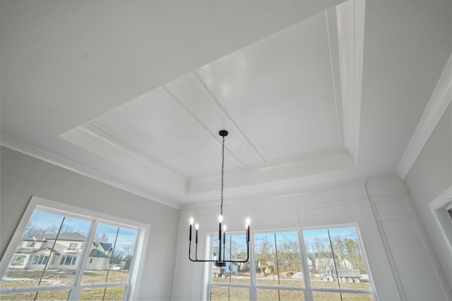 details with an inviting chandelier, a raised ceiling, and crown molding