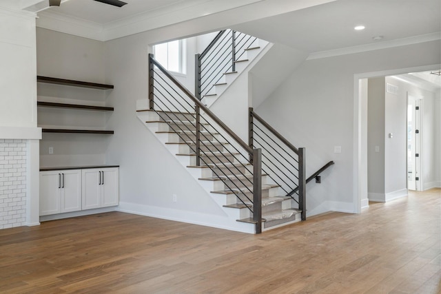 stairs featuring crown molding, baseboards, and wood finished floors