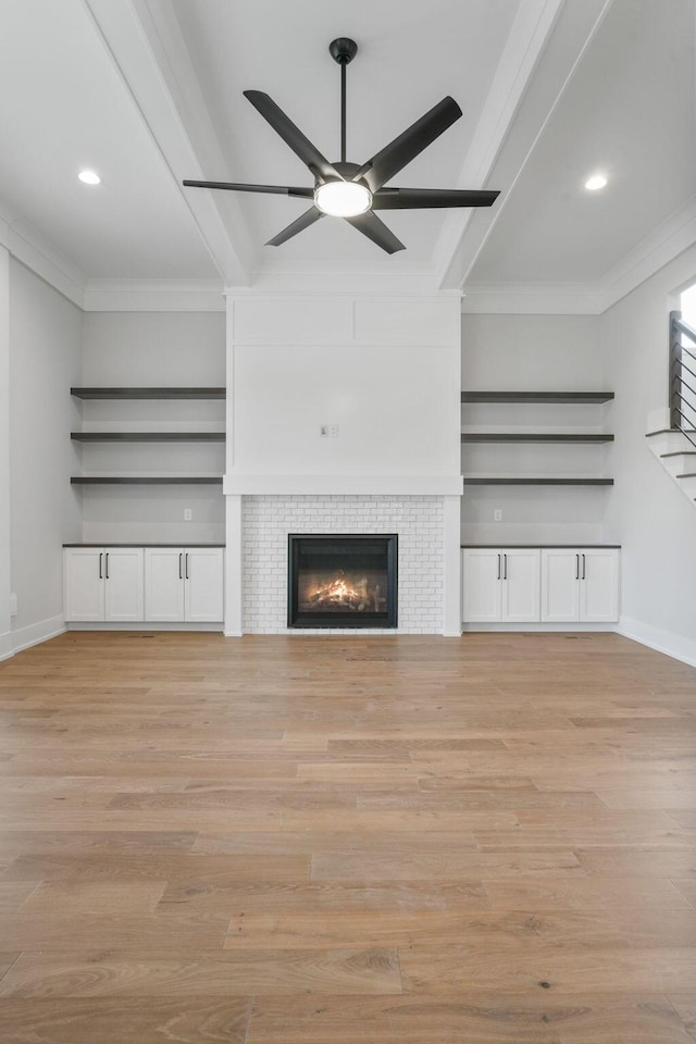 unfurnished living room featuring light wood finished floors, crown molding, and beam ceiling