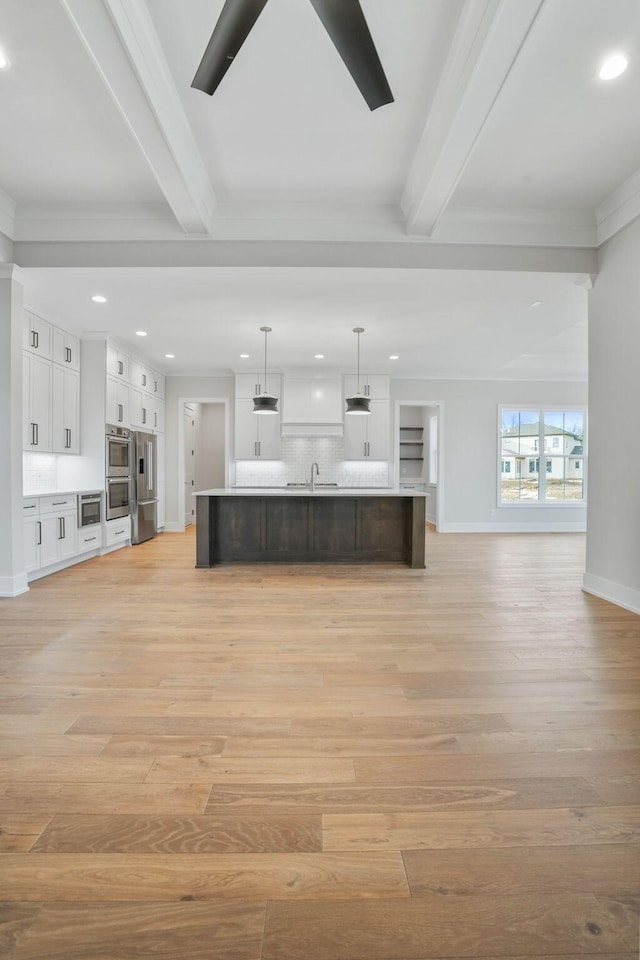 unfurnished living room with recessed lighting, a sink, beam ceiling, and light wood-style floors