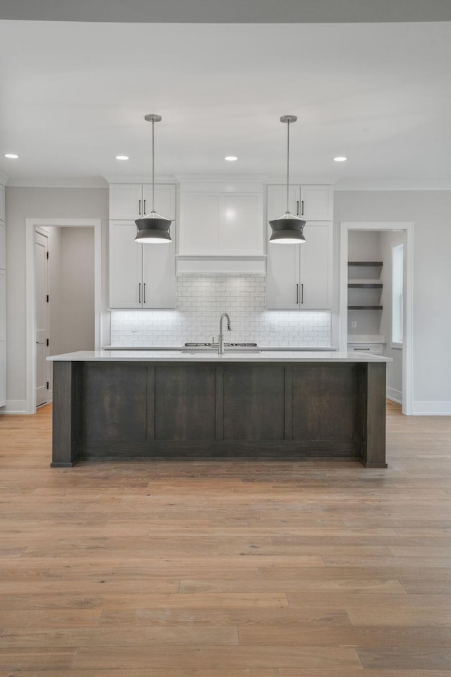 kitchen with light countertops, a center island with sink, and hanging light fixtures