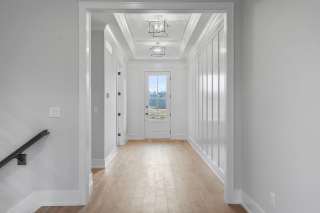 doorway to outside featuring ornamental molding, a chandelier, light wood-style floors, and baseboards