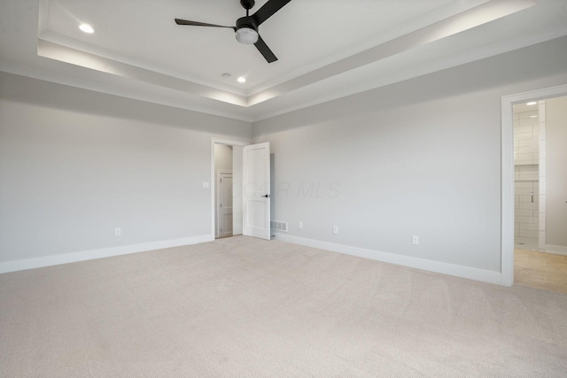 spare room with a tray ceiling, light colored carpet, visible vents, and recessed lighting