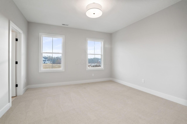 empty room featuring visible vents, light carpet, and baseboards