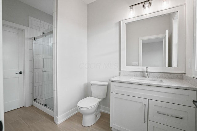 bathroom featuring toilet, wood finished floors, vanity, baseboards, and a shower stall