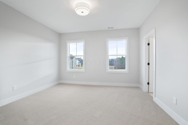 spare room featuring visible vents, light carpet, and baseboards