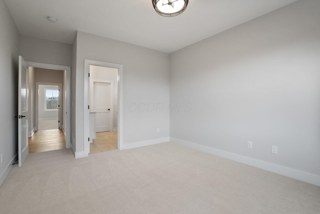 unfurnished bedroom featuring baseboards and light colored carpet