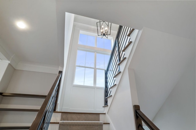 stairway with a notable chandelier