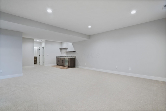 unfurnished living room with baseboards, light colored carpet, and recessed lighting