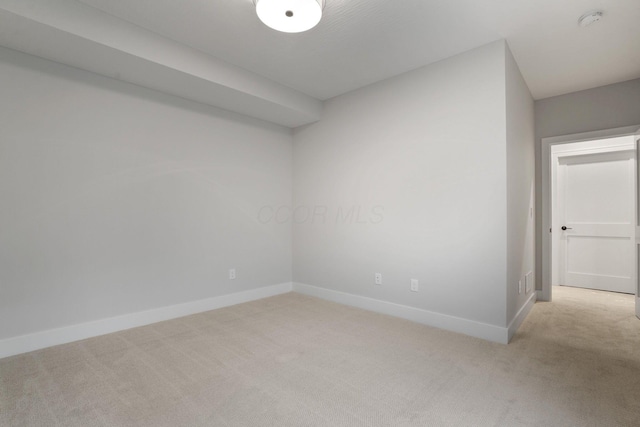 empty room featuring baseboards and light colored carpet