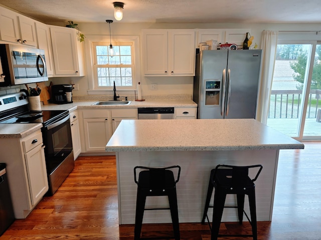 kitchen with white cabinets, wood-type flooring, stainless steel appliances, and sink