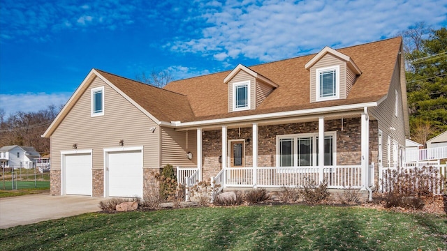 new england style home with a garage, covered porch, and a front lawn