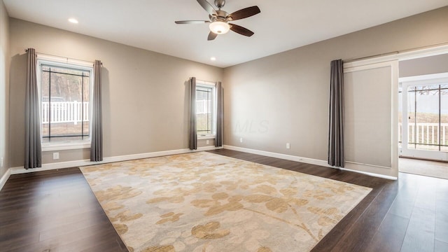 empty room with plenty of natural light, ceiling fan, and dark hardwood / wood-style flooring