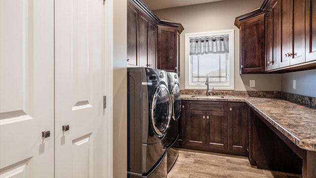 washroom featuring cabinets, sink, washing machine and dryer, and light hardwood / wood-style flooring