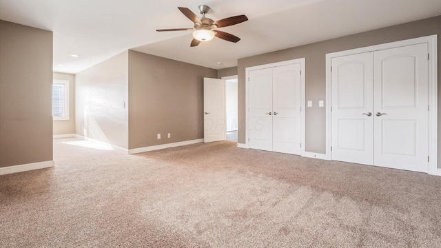 unfurnished bedroom with multiple closets, ceiling fan, and carpet