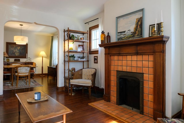 living room featuring a tile fireplace and dark hardwood / wood-style floors