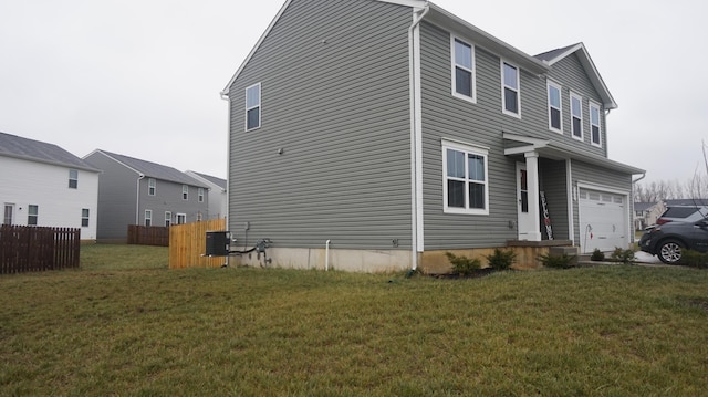 view of home's exterior with a garage, fence, and a lawn