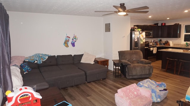 living room with ceiling fan, dark hardwood / wood-style flooring, a textured ceiling, and sink