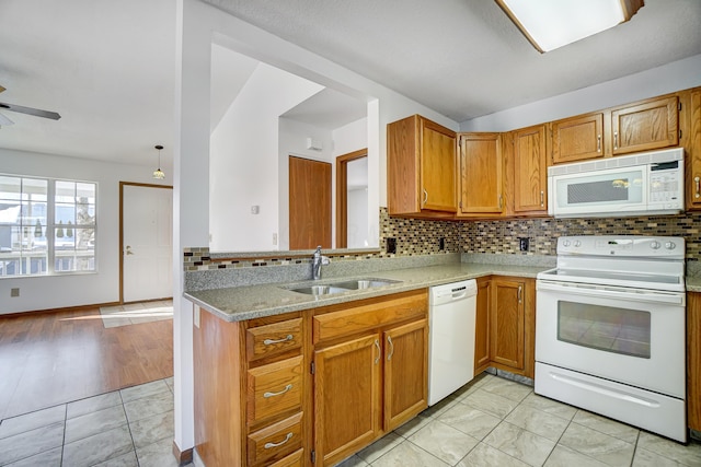 kitchen featuring kitchen peninsula, ceiling fan, white appliances, light stone counters, and sink