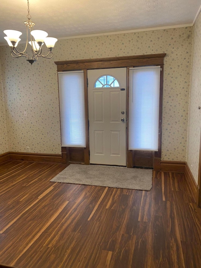 foyer featuring ornamental molding, an inviting chandelier, a textured ceiling, and dark hardwood / wood-style floors