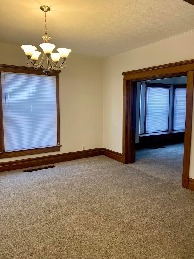 spare room with a textured ceiling, a notable chandelier, and carpet