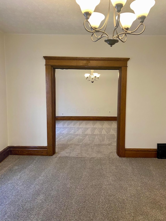 carpeted spare room featuring a notable chandelier