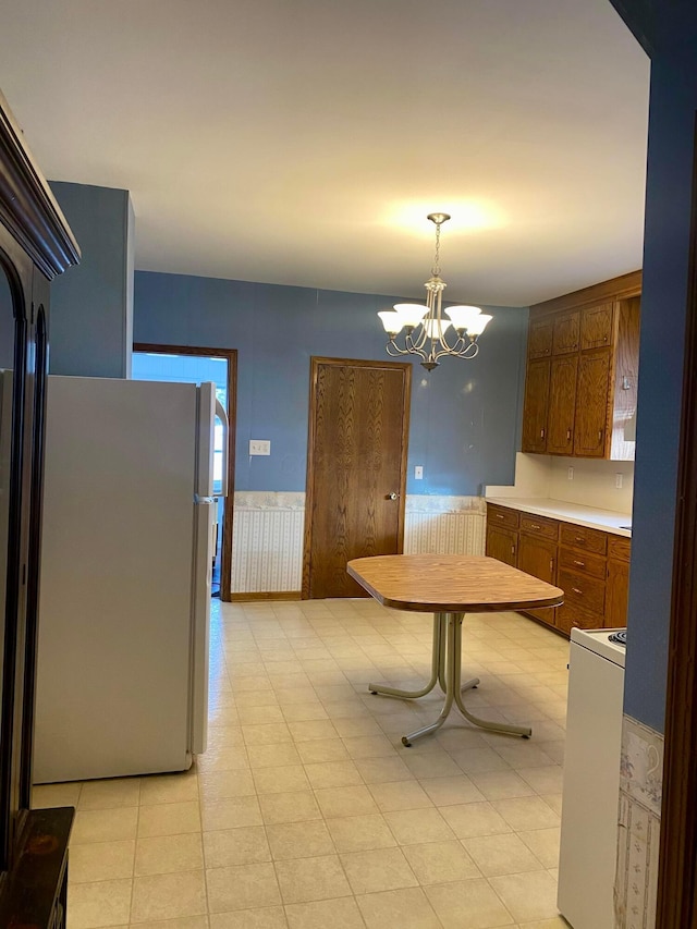 kitchen featuring white appliances, an inviting chandelier, and decorative light fixtures