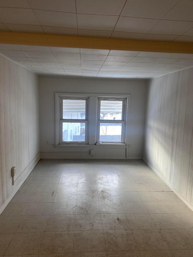 unfurnished room featuring wooden walls