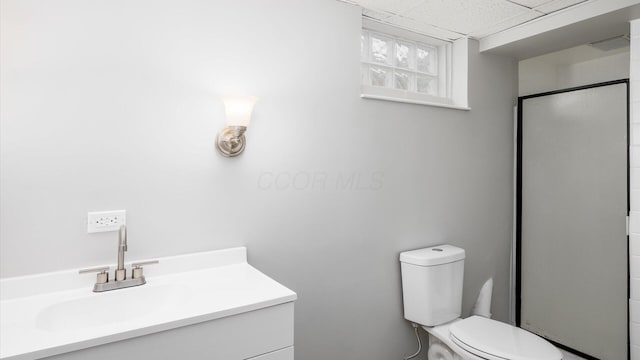 bathroom featuring vanity, toilet, an enclosed shower, and a drop ceiling