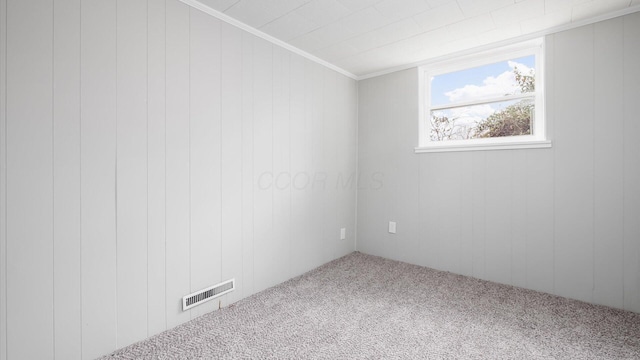 unfurnished room featuring carpet flooring, ornamental molding, and wooden walls