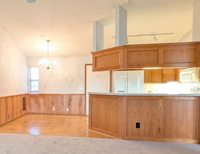 kitchen with an inviting chandelier, pendant lighting, track lighting, white appliances, and light carpet