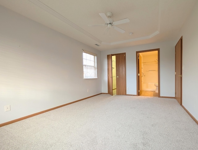 unfurnished bedroom featuring ceiling fan, a tray ceiling, a walk in closet, a closet, and carpet