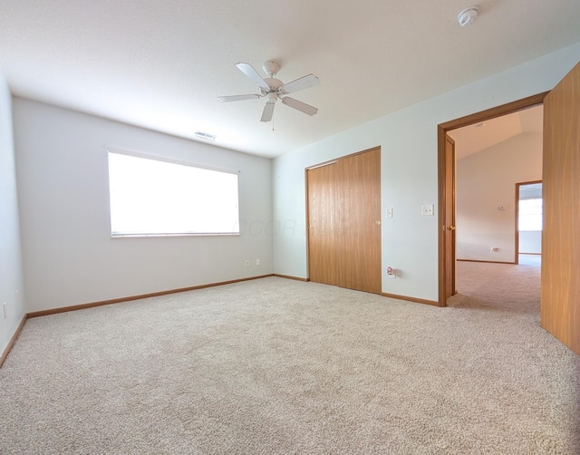 unfurnished bedroom featuring ceiling fan, light colored carpet, lofted ceiling, and multiple windows