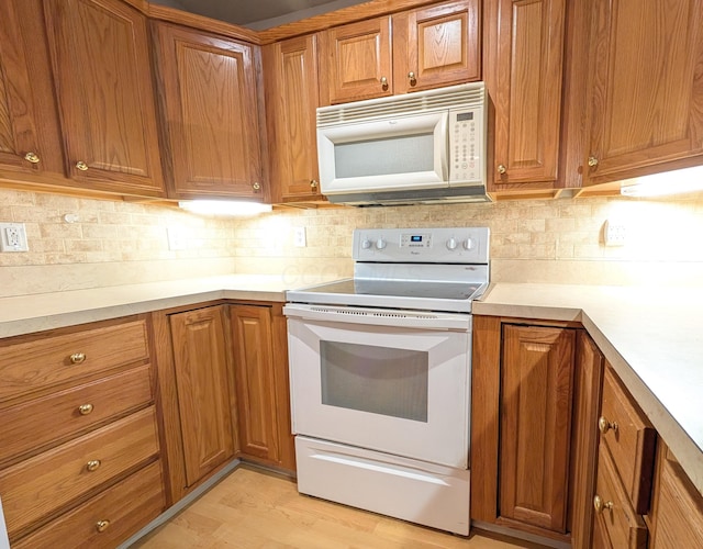 kitchen featuring light wood-type flooring, white appliances, and backsplash