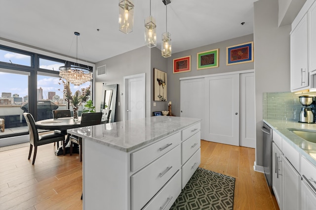 kitchen featuring decorative backsplash, a kitchen island, an inviting chandelier, light hardwood / wood-style flooring, and white cabinetry