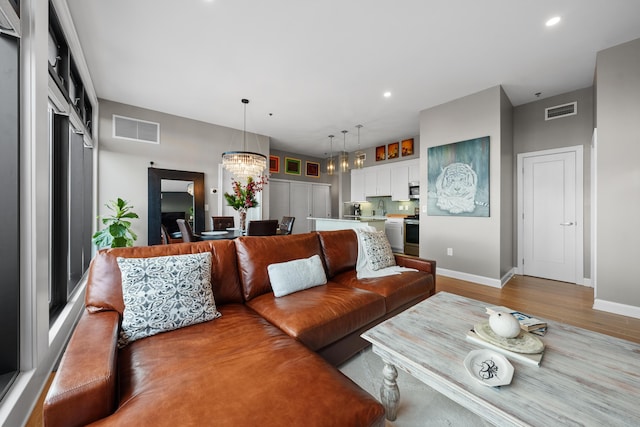 living room featuring light wood-type flooring and an inviting chandelier