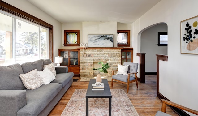 living room with a brick fireplace and light hardwood / wood-style flooring