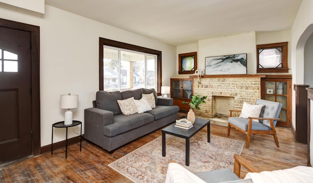 living room with dark hardwood / wood-style floors and a brick fireplace