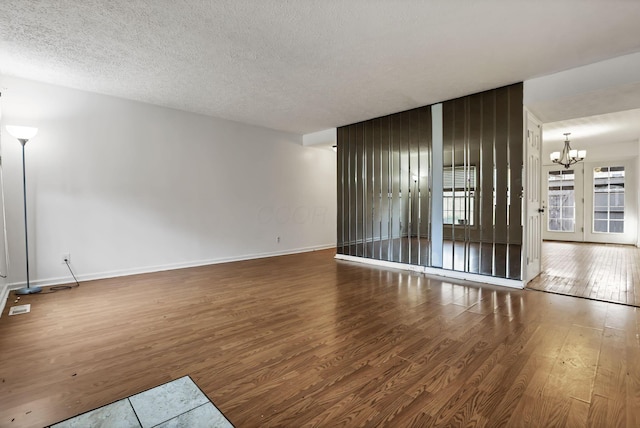 spare room with hardwood / wood-style flooring, a textured ceiling, and an inviting chandelier