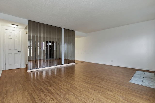 unfurnished room with a textured ceiling and light wood-type flooring