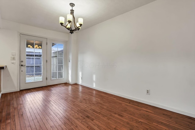 empty room featuring hardwood / wood-style floors, a notable chandelier, and a healthy amount of sunlight